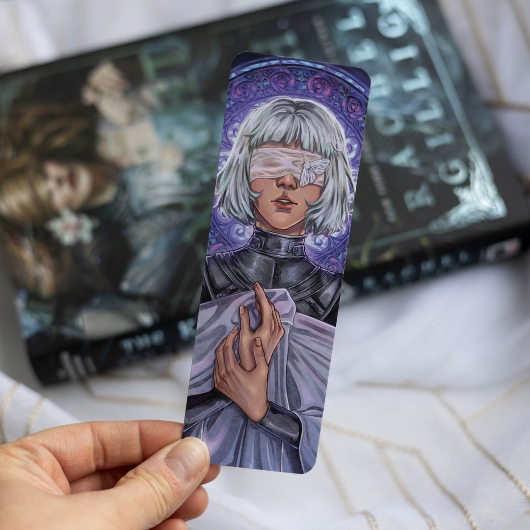Purple bookmark with Sybil from Knight and the Moth in her armor and shroud in front of a stained glass window, held over The Knight and the Moth.