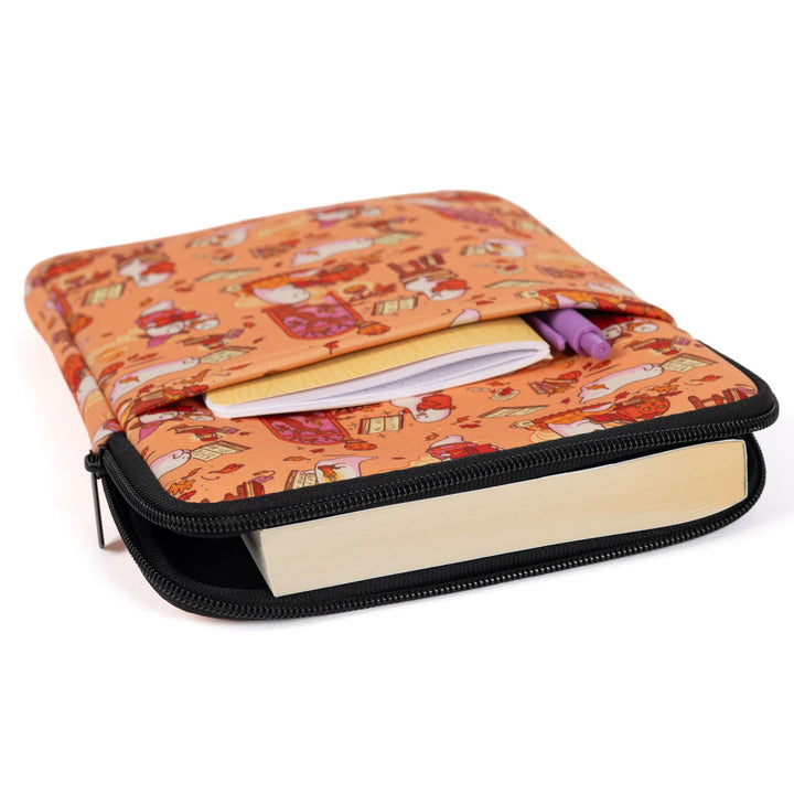 Medium zippered booksleeve with orange background and ghosts reading books, laying flat with a paperback book sticking out. 