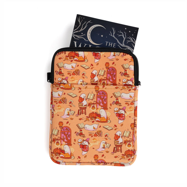 Medium zippered booksleeve with orange background and ghosts reading books. A paperback is sticking out.