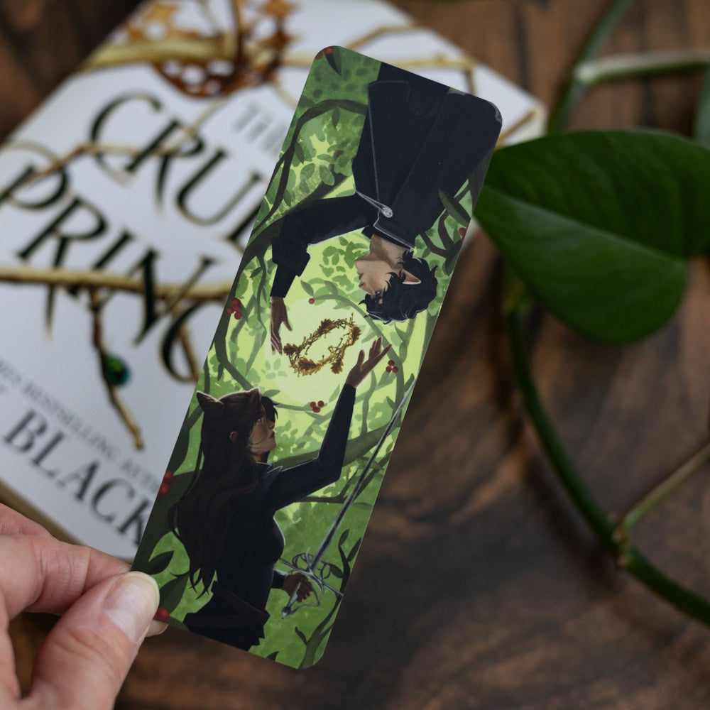 Green bookmark of Jude and Cardan and the Blood Crown held over the book The Cruel Prince.