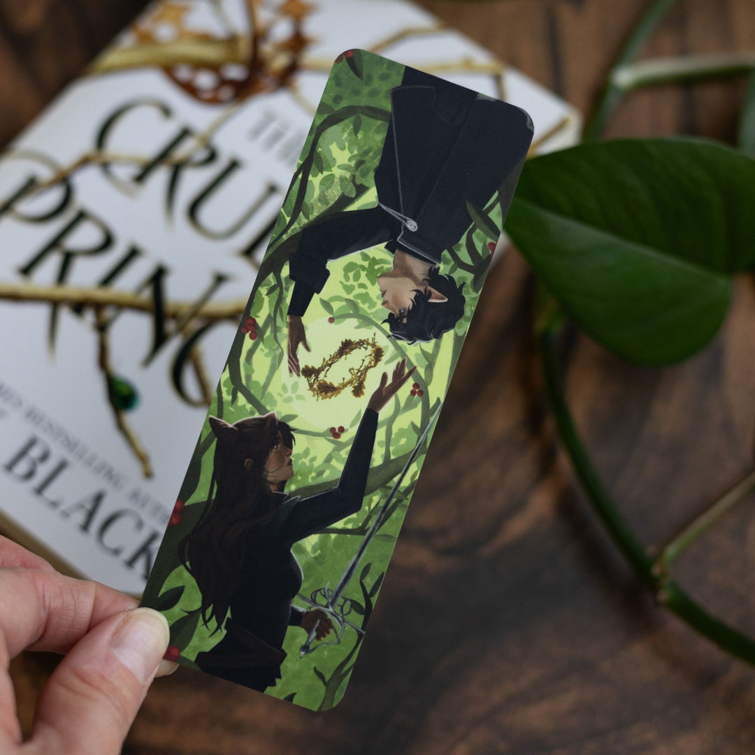 Green bookmark of Jude and Cardan and the Blood Crown held over the book The Cruel Prince.