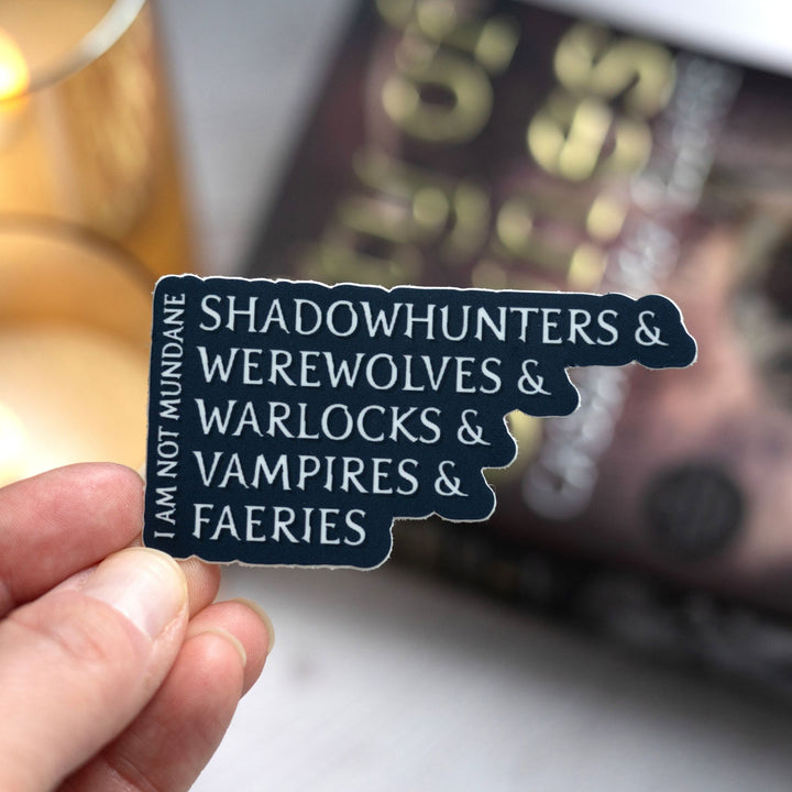 Sticker held over City of Bones that reads ‘I am not mundane. Shadowhunters, and werewolves, and warlocks, and vampires, and faeries.’