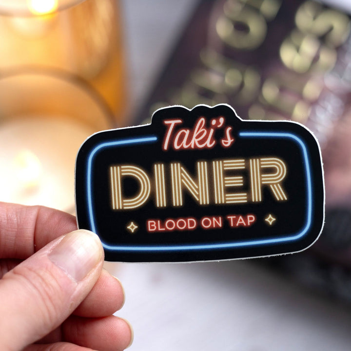  Shadowhunter’s sticker reads: ‘Taki’s Diner, blood on tap’ in the style of a neon sign, held over City of Bones.