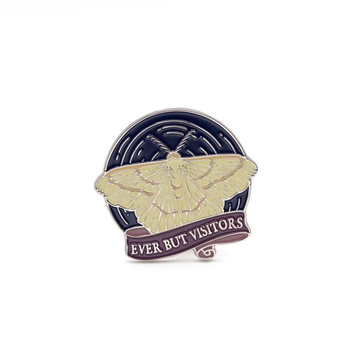 Circular enamel pin inspired by The Knight and the Moth. The pin is a moth flying on a blue sky over a ribbon banner with the quote ‘Ever But Visitors.’