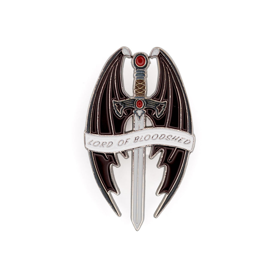 Enamel pin of a sword with a red stone and pommel, surrounded by bat wings that reads ‘Lord of Bloodshed’ on a white ribbon. 