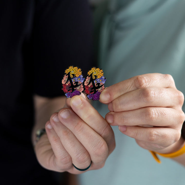  Black enamel pin of parabatai rune from Shadowhunters, surrounded by flowers being held together by two different hands.