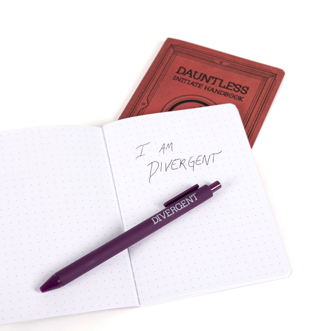 Red Dauntless Initiate Handbook A6 journal behind an open A6 dot grid journal with purple pen and handwritten note: I am Divergent.