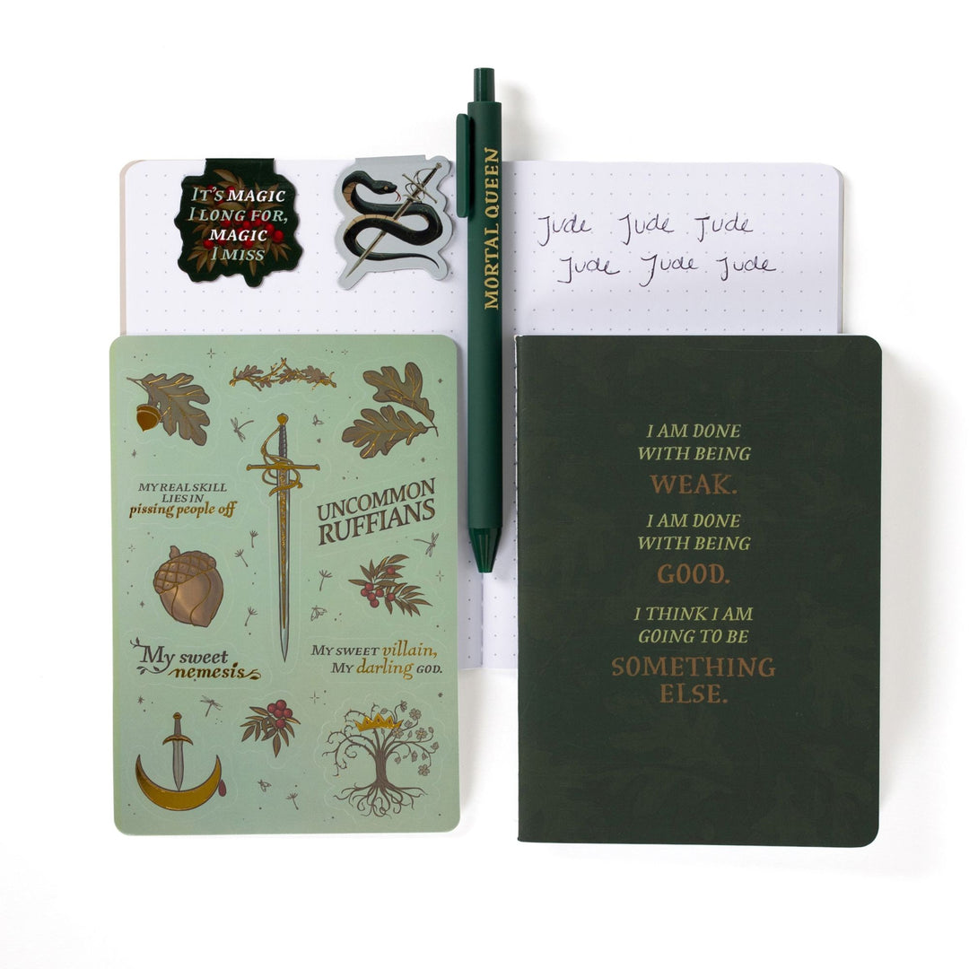 Gift set opened: Dot grid A6 journal open with pen, Serpent King Cardan & 'It’s magic I long for, magic I miss’ magnetic bookmarks, The Cruel Prince sticker sheet, A6 green ‘I am done being weak’ journal.

