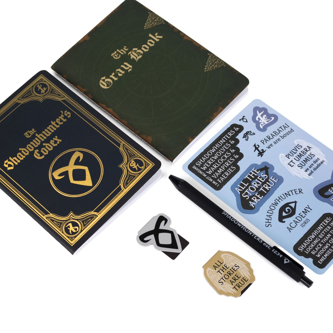 Gift set laid out: A6 Shadowhunters Codex and The Gray Book journals, Shadowhunters sticker sheet, ‘All the stories are true’ & Enkeli rune magnetic bookmarks, black pen.
