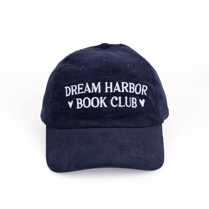 Dark blue, corduroy baseball cap with white embroidered text that reads ‘Dream Harbor Book Club.’ There are hearts around ‘Book Club.’