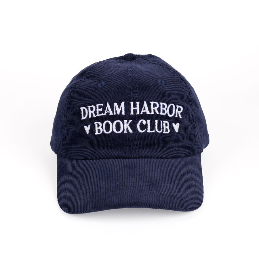 Dark blue, corduroy baseball cap with white embroidered text that reads ‘Dream Harbor Book Club.’ There are hearts around ‘Book Club.’