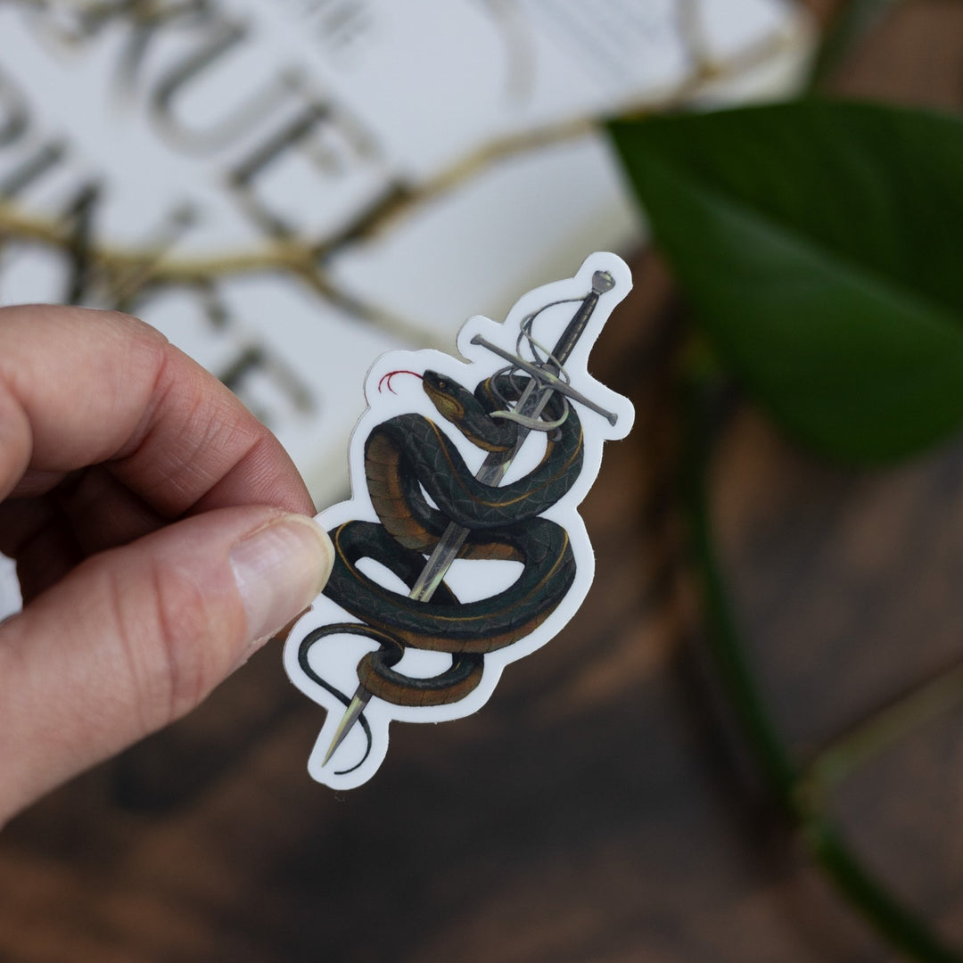 Sticker of Cardan from The Cruel Prince in serpent form, wrapped around the sword Nightfell, held above The Cruel Prince.