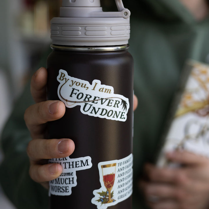 The Cruel Prince quote sticker on a black water bottle: ‘By you, I am forever undone’ with Cardan’s tail. 