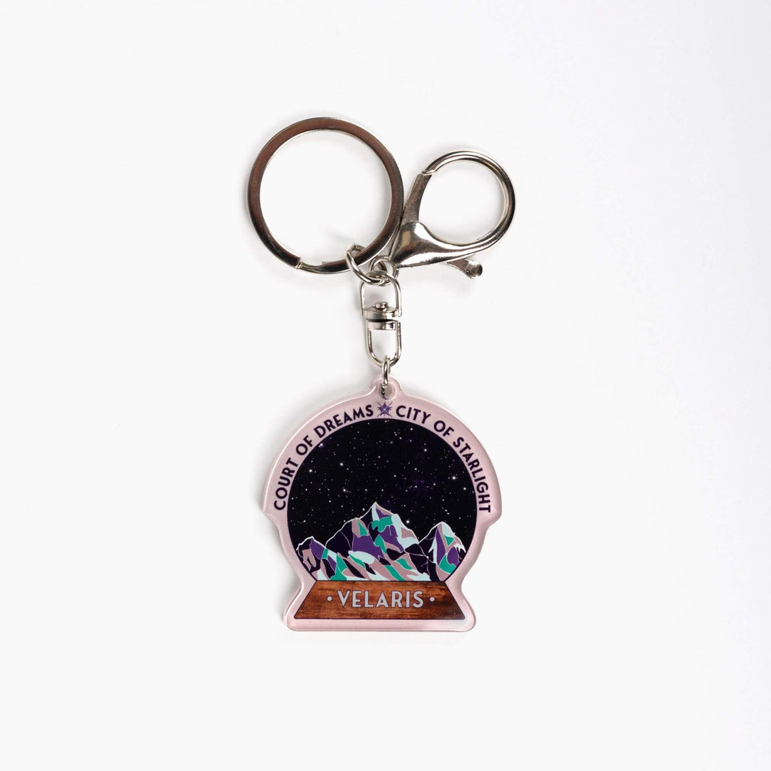  Acrylic keychain of snow globe with mountains against the night sky. 'Court of Dreams City of Starlight' above it. ‘Velaris’ on the base.

