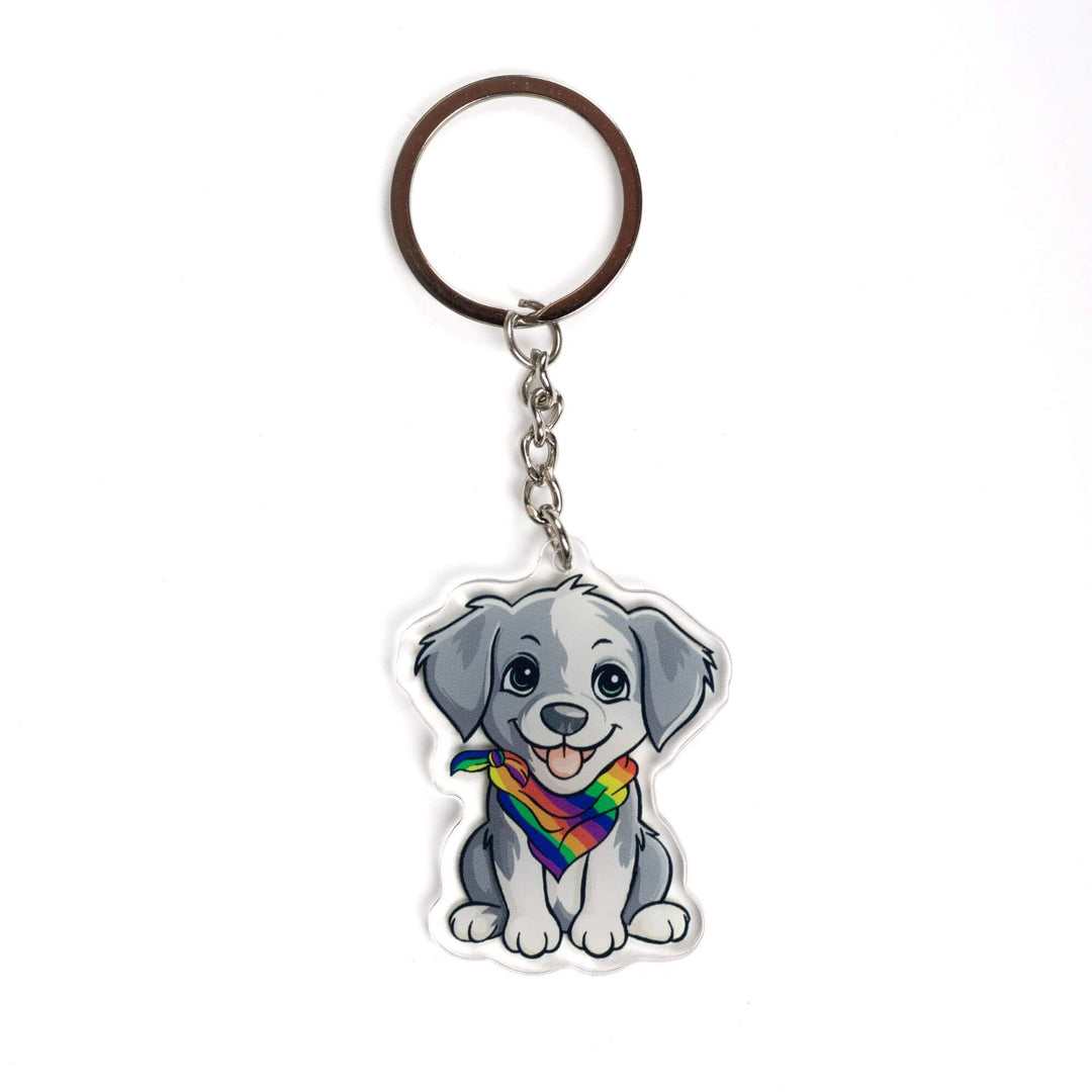 Acrylic keychain of a grey and white puppy, sitting happily and wearing a rainbow pride bandana.
