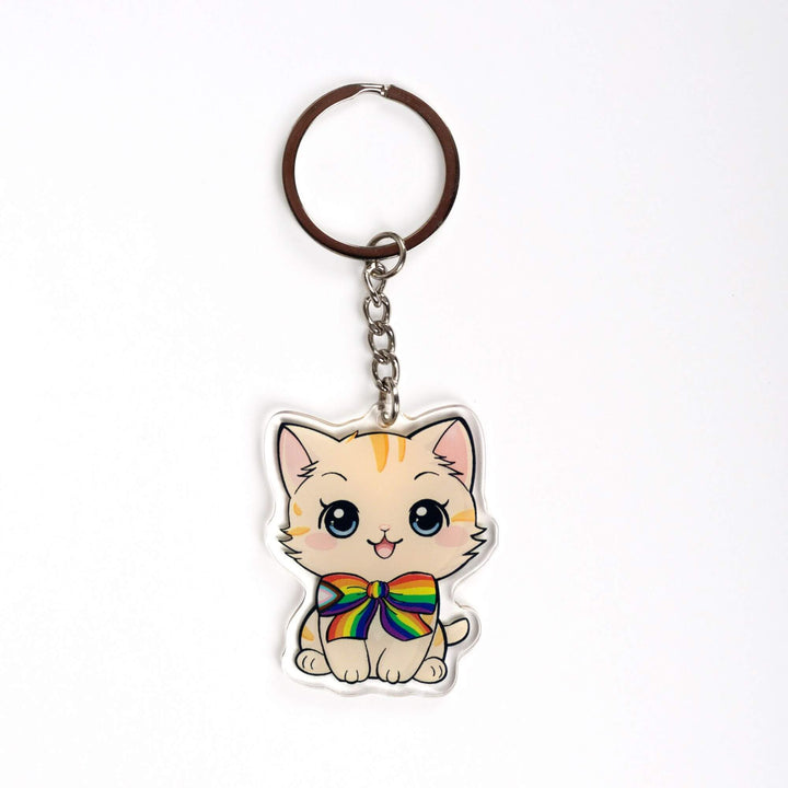 Acrylic keychain of a cream colored kitten with order stripes, sitting happily and wearing a progress pride flag bow tie.