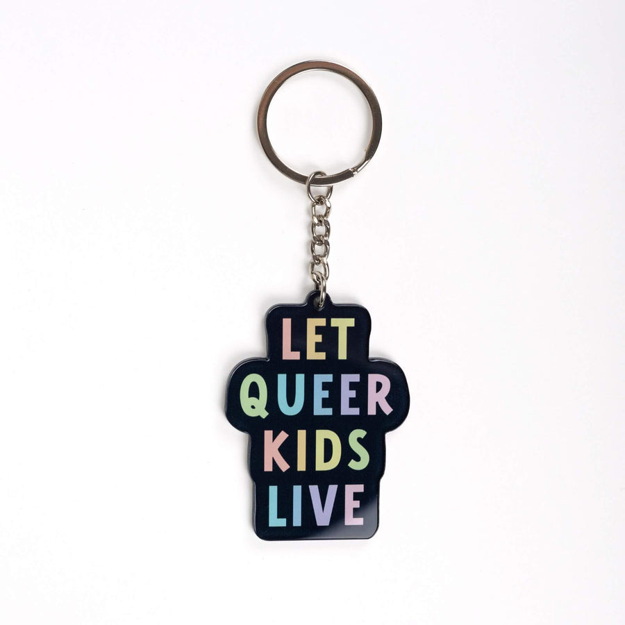 Acrylic keychain that says ‘Let queer kids live.’ The words are a pastel rainbow on a black background.