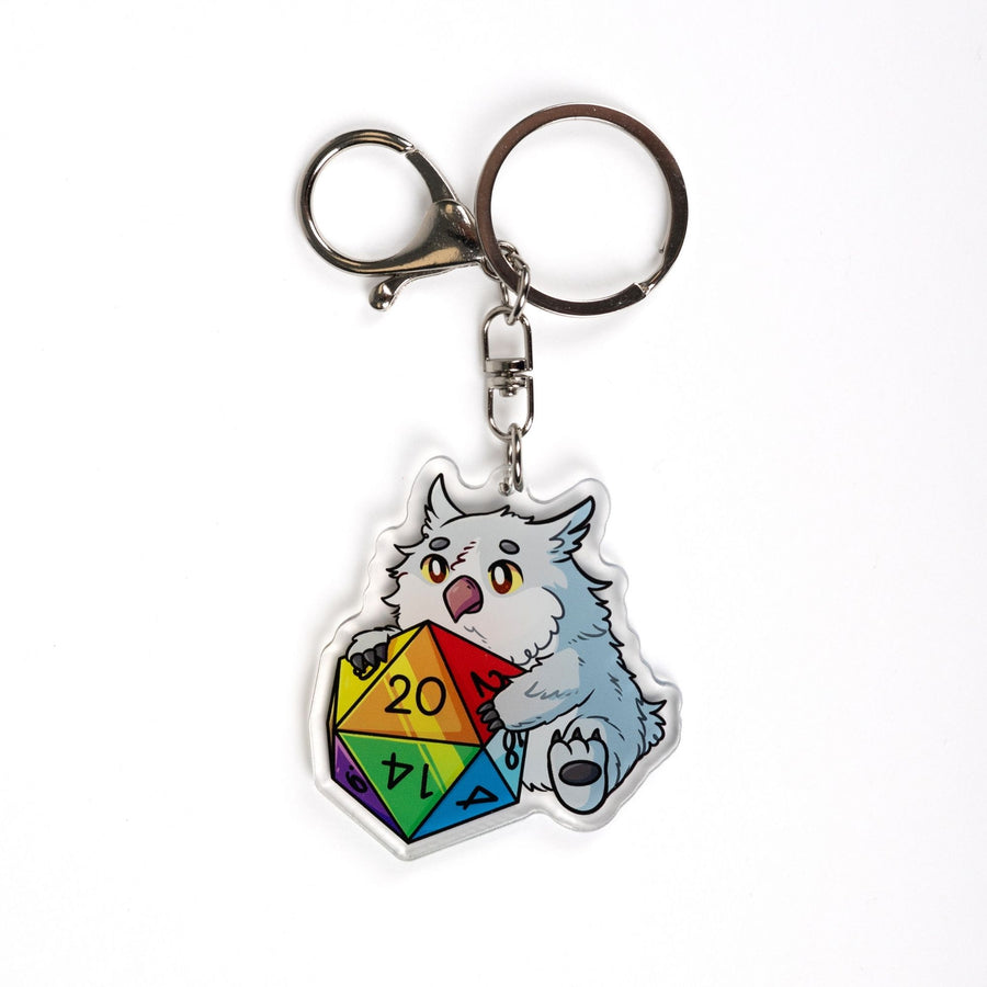 Acrylic keychain of a baby Owlbear holding a rainbow d20. The number 20 is facing up.