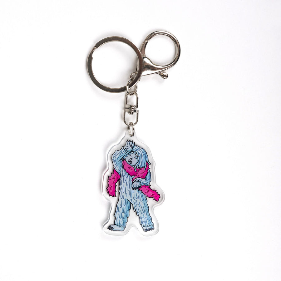  Acrylic keychain of David the Yeti wearing a pink boa and hand dramatically against their head. From House in the Cerulean Sea.
