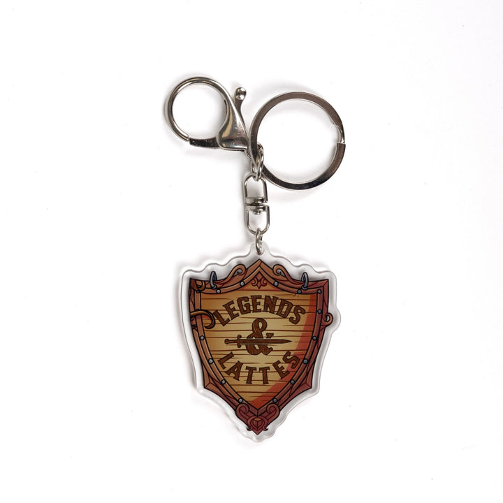 Acrylic keychain of a wooden shield with ‘Legends & Lattes’ shop logo on it. From Legends & Lattes by Travis Baldree.