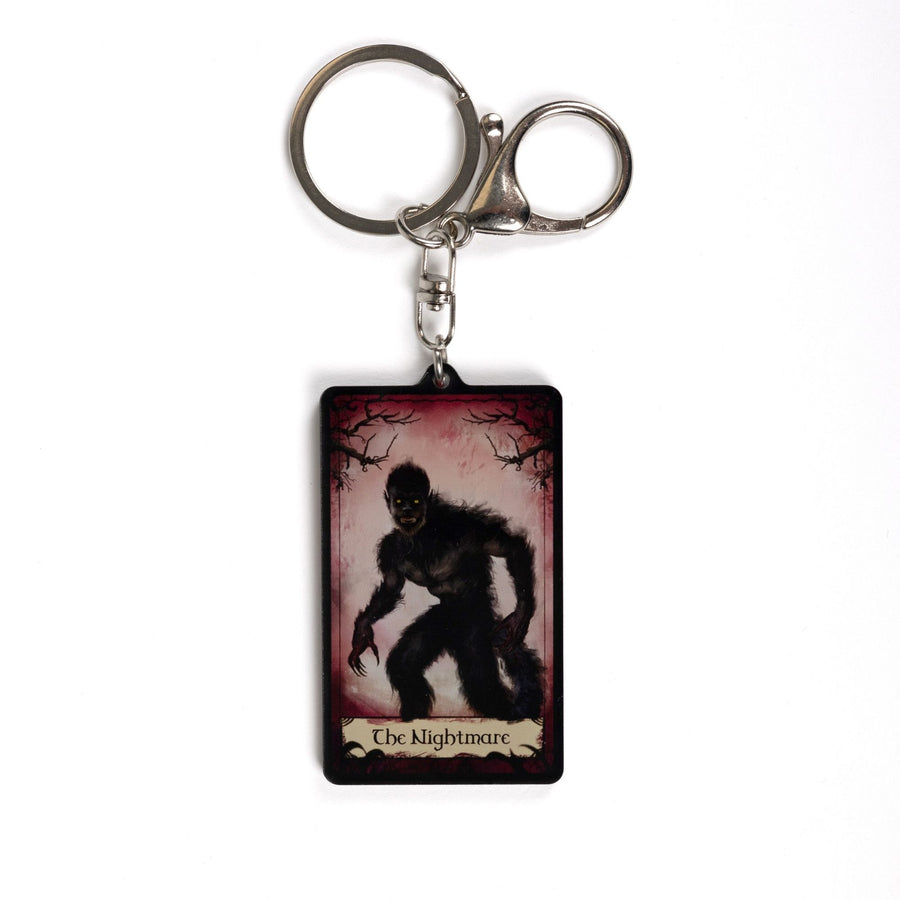 Acrylic keychain of a red tarot card that says ‘The Nightmare’ across the bottom. The card has creepy branches at the top and a monster in frame.