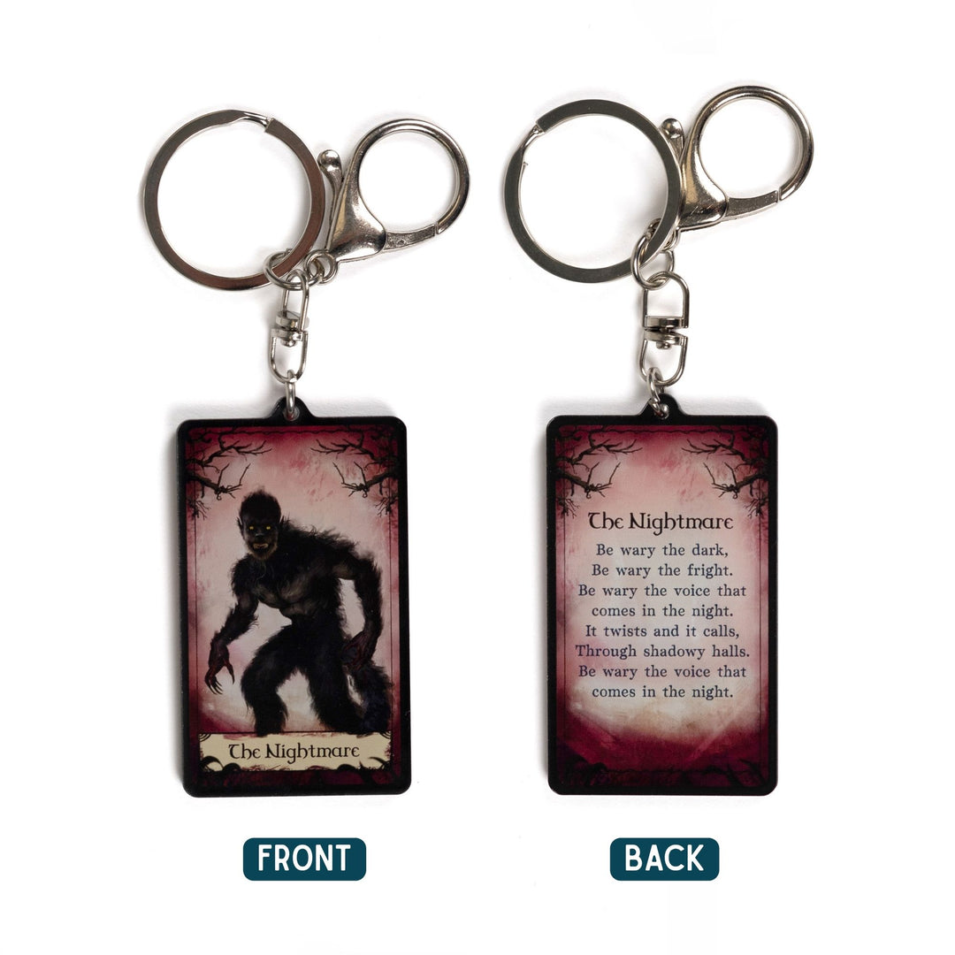 2 acrylic keychains of a tarot card. One says ‘The Nightmare’ with a monster below it. The other is a quote from One Dark Window by Rachel Gillig. 
