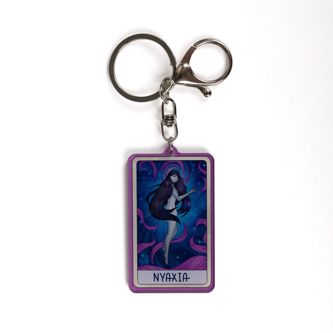 Acrylic keychain of a woman with long dark hair, black eyes floating in a night sky with purple swirls with ‘Nyaxia’ at the bottom.
