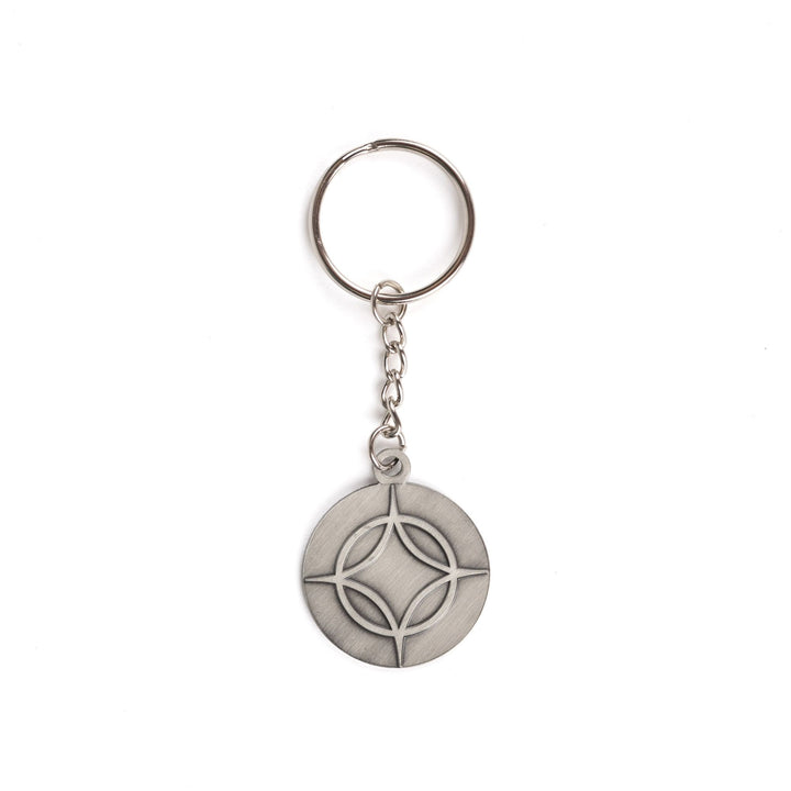 Metal keychain of a circle with a four point star over top. From Legendborn by Tracey Deonn. 
