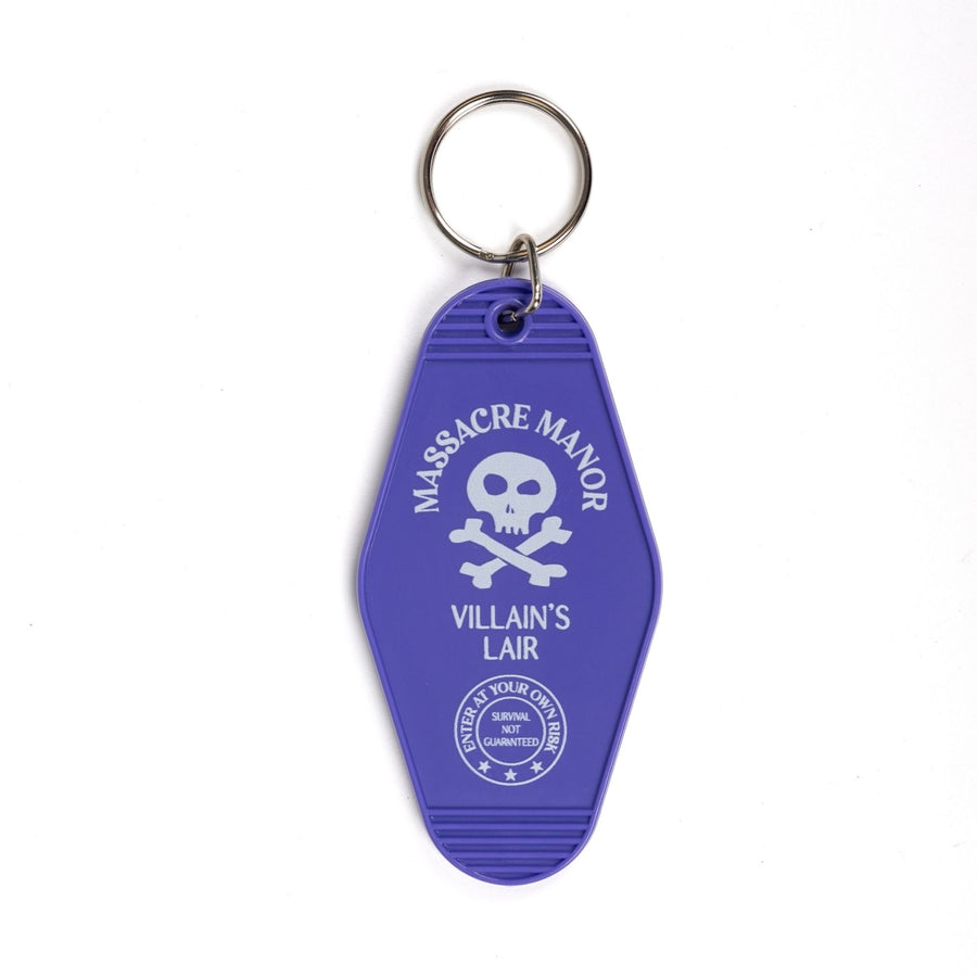 Purple plastic keychain with ‘Massacre Manor’ in white above a skull and crossbones and ‘Villain’s lair. Enter at your own risk. Survival not guaranteed’ below. 