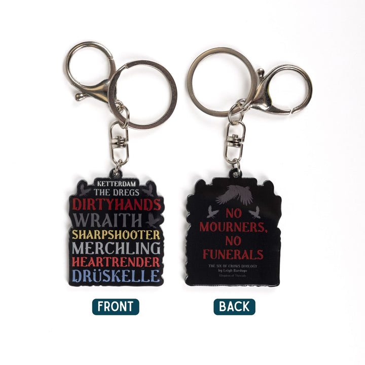 2 acrylic keychains. One side says ‘Ketterdam, The Dregs, Dirtyhands, Wraith, Sharpshooter, Merchling, Heartrender, Druskelle.’ The other ‘No Mourners. No funerals.’