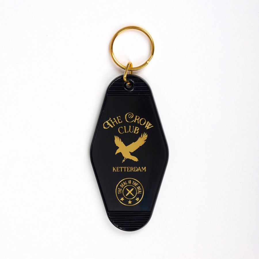  Black motel-style keychain with golden lettering and a golden crow for ‘The Crow Club. Ketterdam.’ ‘The deal is the deal’ in a small circle at the bottom.