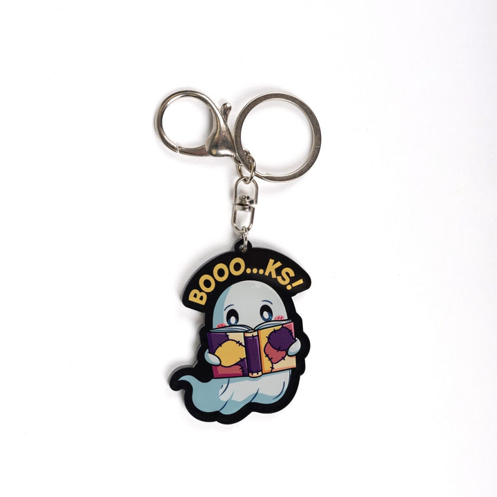Acrylic keychain of a ghost reading a book with the words ‘Booo…ks!’ over it in yellow.