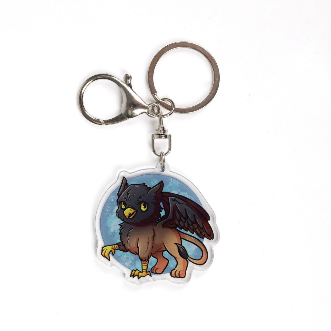 Acrylic Keychain of a baby griffon with a black head and wings and a brown body. From Tomes & Tea.

