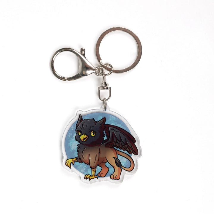 Acrylic Keychain of a baby griffon with a black head and wings and a brown body. From Tomes & Tea.
