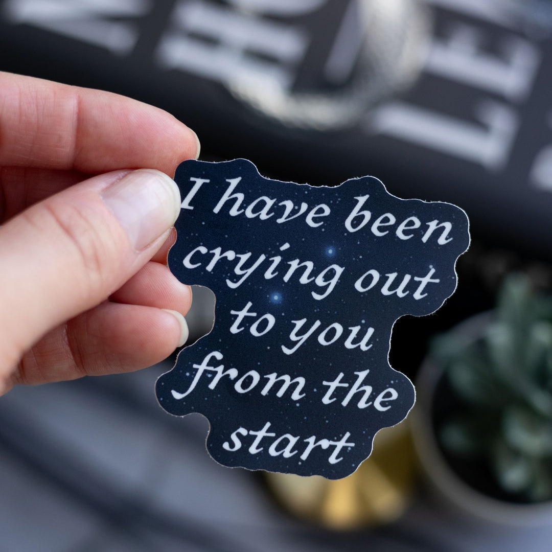   Quote sticker from Ninth House by Leigh Bardugo ‘ I have been crying out to you from the start,’ held above Ninth House.