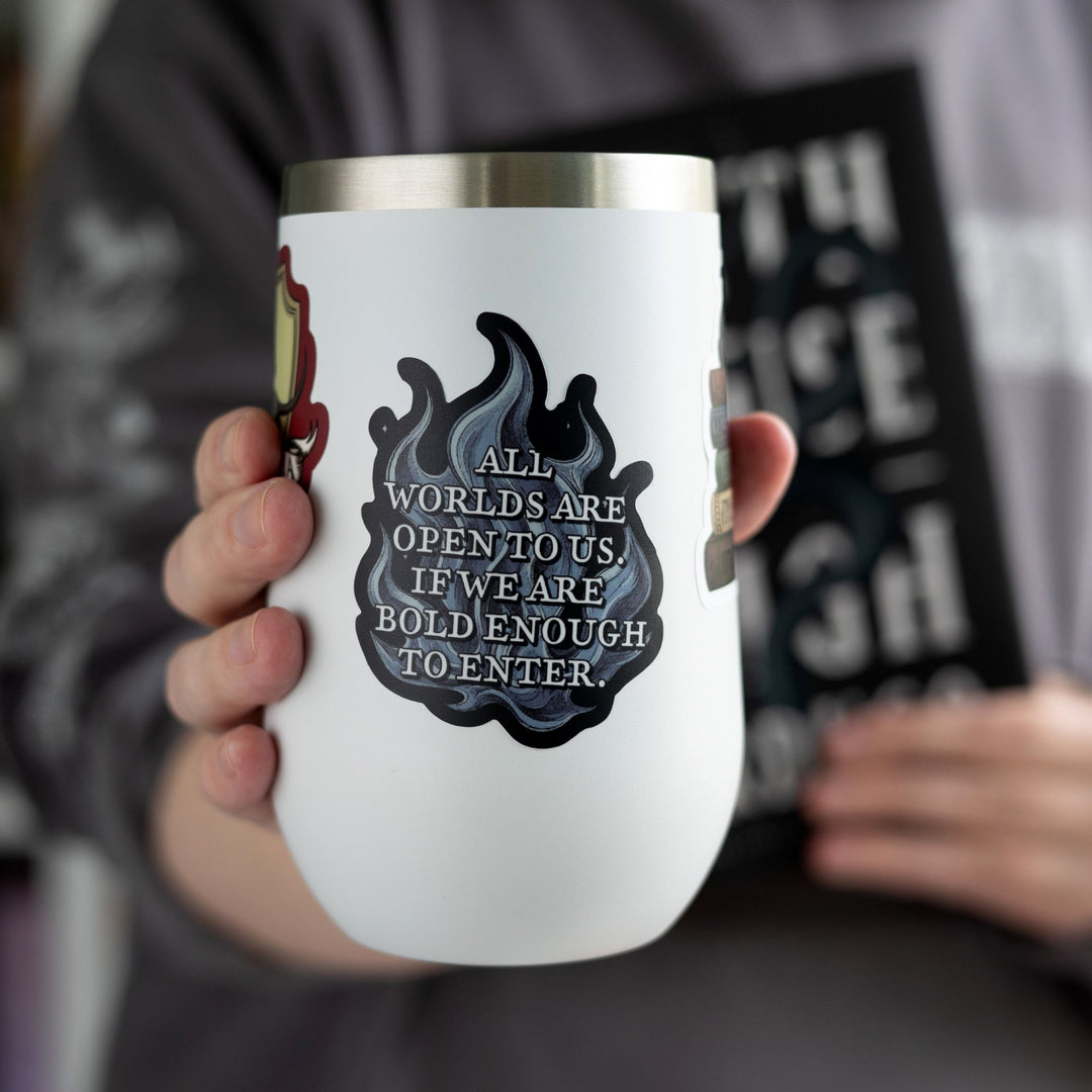  Quote sticker from Ninth House on blue flames that reads ‘ All worlds are open to us. If we are bold enough to enter,’ on a white tumbler.
