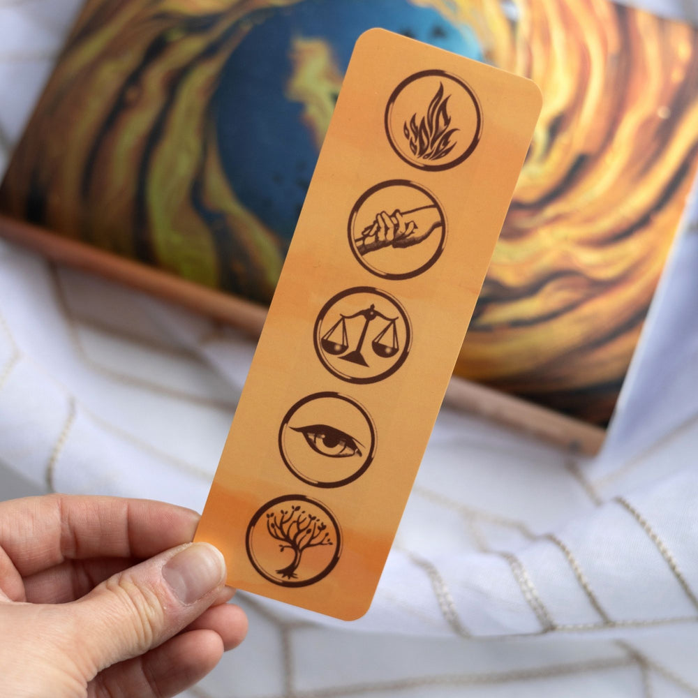 Gold bookmark with the five faction symbols from Divergent held over the anniversary edition of the book.