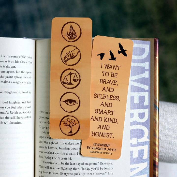 Two gold bookmarks in an open book: one with Divergent’s faction symbols. On the other ‘I want to be brave and selfless and smart and kind and honest.’