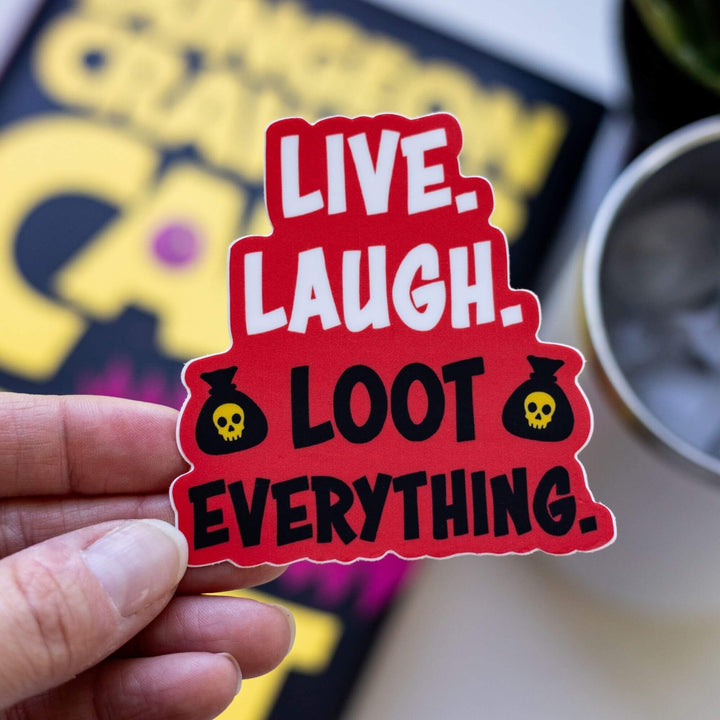 Sticker of ‘Live. Laugh. Loot Everything.’ Text on a red background with money bags with yellow skulls next to Loot Everything. Held over Dungeon Crawler Carl