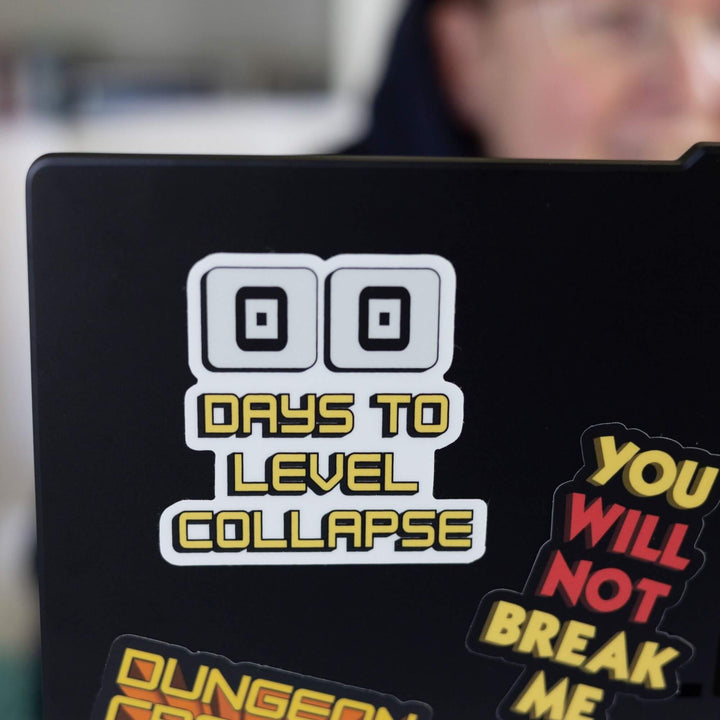 Sticker of two zeros are above ‘Days to level collapse’ in yellow. It is a countdown. Displayed on the corner of  black laptop