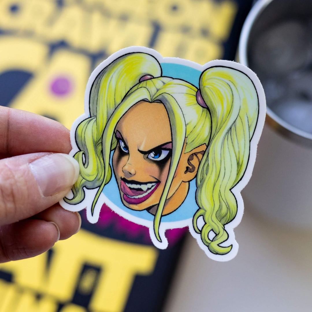  Sticker of Samantha’s head. Her hair is in pigtails. She has dark eyeliner on and fangs. She’s grinning wickedly. Held over Dungeon Crawler Carl.
