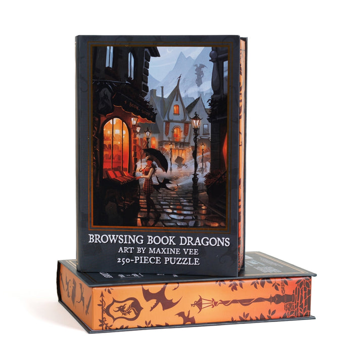 Book-shaped black box for Browsing Book Dragons 250-piece puzzle. Art on the front is a rainy day street scene outside a bookstore with a woman and small dragons.