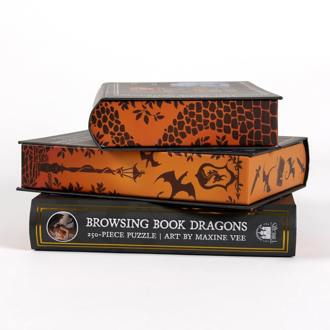 Stack of 3 puzzle boxes showing all sides. Orange edges with details of cobblestone and a lampost and the spine of the box reads Browsing Book Dragons 250-piece puzzle.
