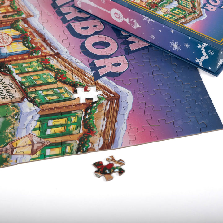 Close up of completed puzzle of Main Street in Dream Harbor, decorated for the holidays, with one piece missing.