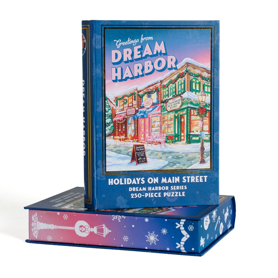 Book-shaped black box for Holidays on Main Street Dream Harbor 250-piece puzzle. Art on the front is of Main Street in the snow.