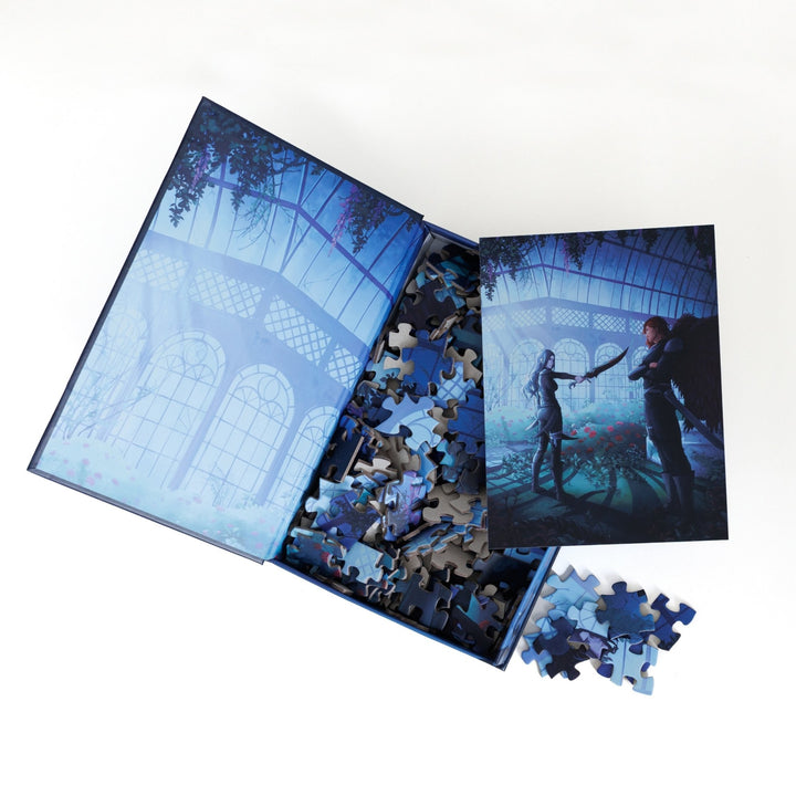An open book-shaped box reveals puzzle pieces. Inner art on the top flap greenhouse at night. An art print of Oraya and Raihn atop the pieces.