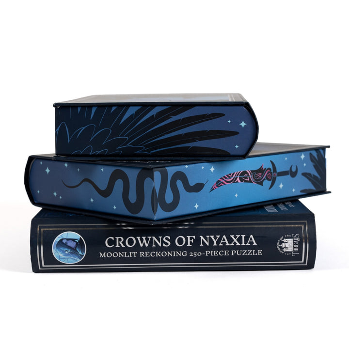 Stack of 3 puzzle boxes showing all sides. Blue edges with a black sword, snake, and feathers and the spine of the box reads Crowns of Nyaxia Moonlit Reckoning 250-piece puzzle.