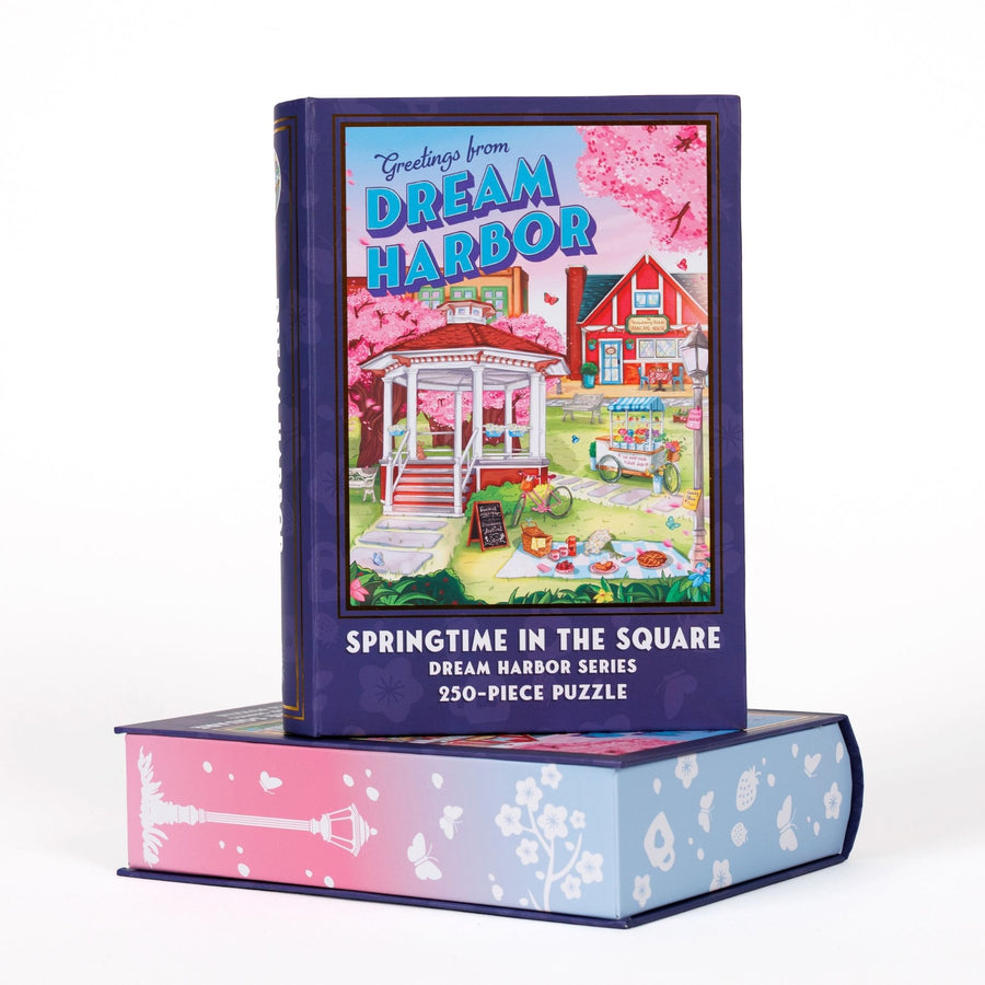 Book-shaped black box for Springtime in the Square Dream Harbor Series 250-piece puzzle. Art on the front is of the town square’s gazebo in spring.