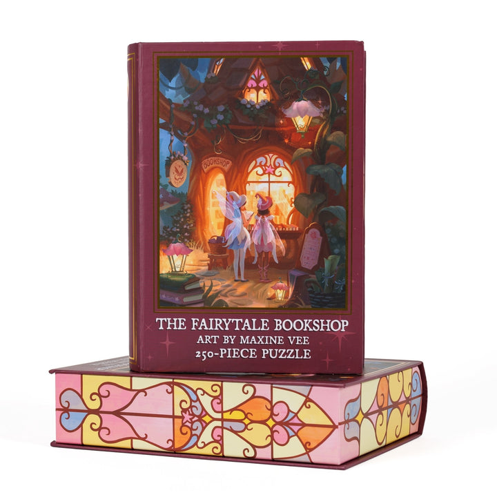 Book-shaped black box for ‘The Fairytale Bookshop Art by Maxine Vee 250-piece puzzle.’ Art on the front is of two fairies looking into the window of a woodland bookstore.