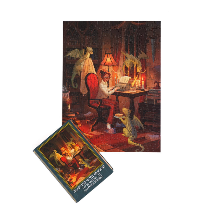 Full completed puzzle of a woman at a writing desk with three small dragons and book-shaped box  with matching art for  ‘Drafting with Dragons Art by Maxine Vee 250-piece puzzle.’